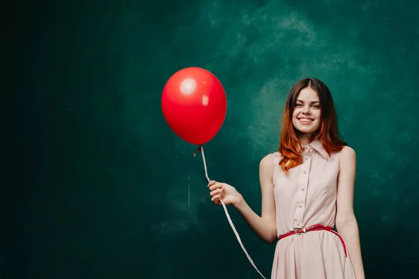 Mujer alegre con globo rojo vacaciones de fondo verde —  Fotos de Stock