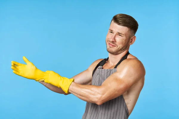Man in schort met opgepompt lichaam rubber handschoenen schoonmaken blauwe achtergrond — Stockfoto