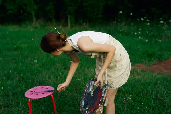 Woman in white dress with palette of paints on nature art drawing — Stock Photo, Image