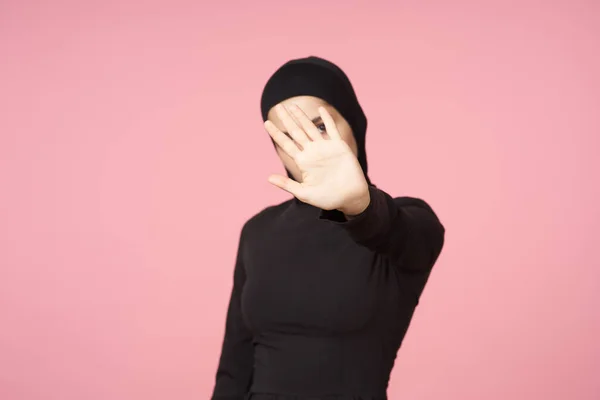 Alegre muçulmano mulher preto hijab posando mão gesto rosa fundo — Fotografia de Stock