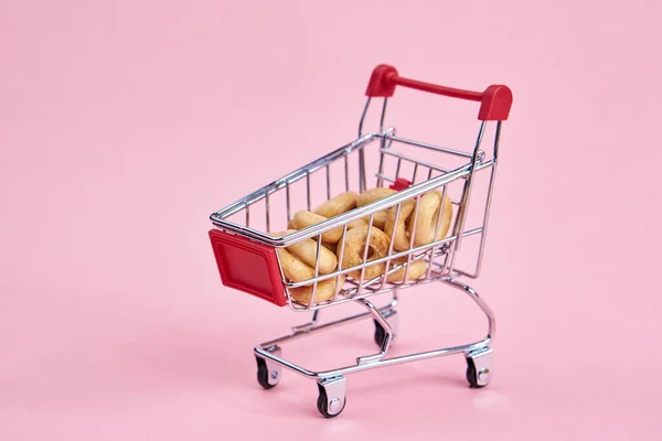 Маленькие тележки супермаркета покупки розовый фон — стоковое фото