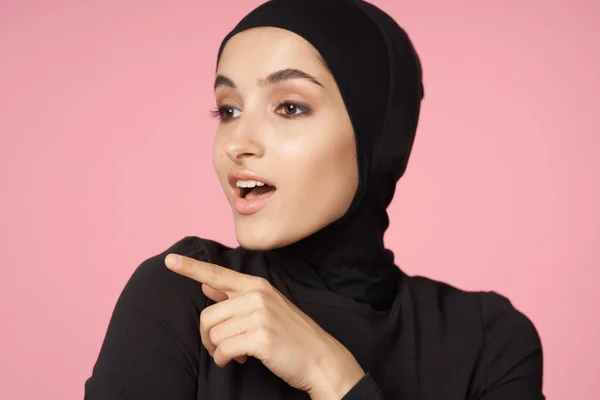 Fröhliche muslimische Frau schwarzer Hijab posiert Handgeste rosa Hintergrund — Stockfoto