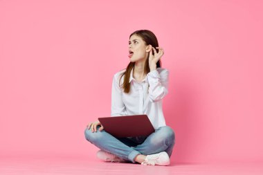Dizüstü bilgisayarı olan bir kadın internet iletişiminde pembe arka planda oturuyor.