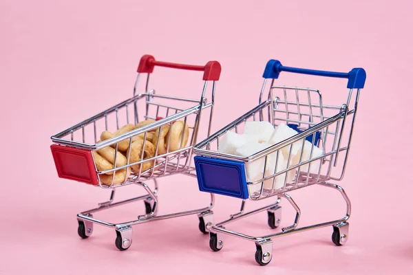 Kis bevásárlókocsik szupermarket vásárlás rózsaszín háttér — Stock Fotó