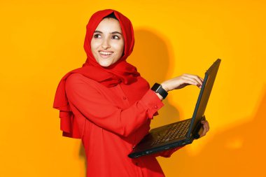Kırmızı tesettür bilgisayar işindeki kadın sarı arkaplan öğreniyor