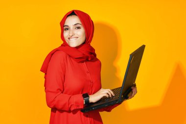 Dizüstü bilgisayarı olan neşeli bir kadın. Teknoloji duyguları sarı arka plan.