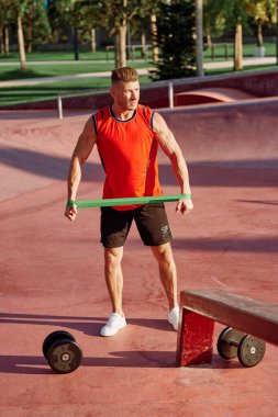 Dambılı erkek sporcu parkta el eğitiminde.