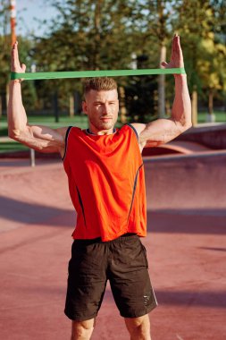 Dambılı erkek sporcu parkta el eğitiminde.