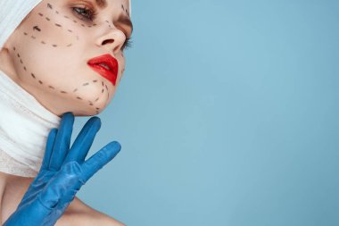 Elinde mavi eldiven şırıngası olan bir insan stüdyo yaşam tarzında yüz gerdirme şekilleri çiziyor.