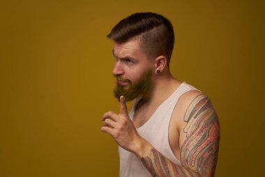 Beyaz tişörtlü maço adam kollarında dövmeler var.