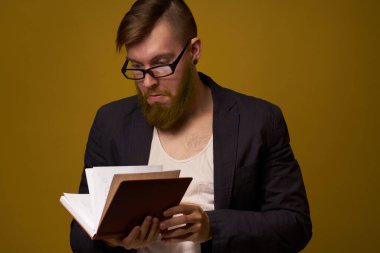 Siyah ceketli sakallı bir adam, elinde bir kitapla.