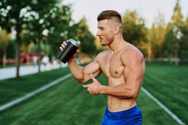 Parktaki egzersiz motivasyonunda kaslı vücutlu atletik bir adam.