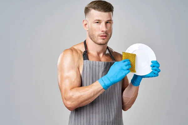 Een man in een schort wast de afwas service huishoudelijk werk — Stockfoto