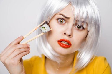 Beyaz peruklu güzel bir kadın ve Japon yemek çubuklarıyla suşi.