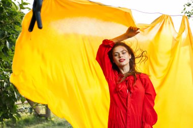 Sarı kumaşın yanındaki kadınlar kırmızı elbise giyerler.