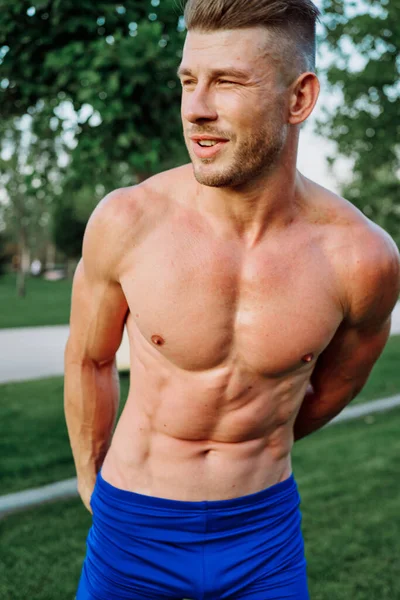 Sporty muscled man with naked torso in a workout park — Stock Photo, Image