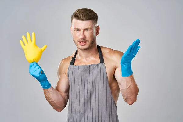 Opgepompte man in schort rubberen handschoenen schoonmaken van huishoudelijk werk — Stockfoto