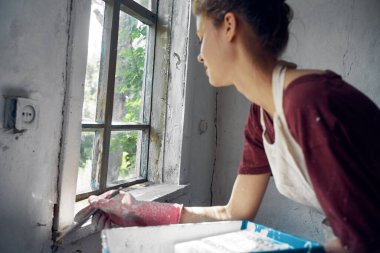 Kadın ressam pencerenin iç tarafında ev onarımı yapıyor.