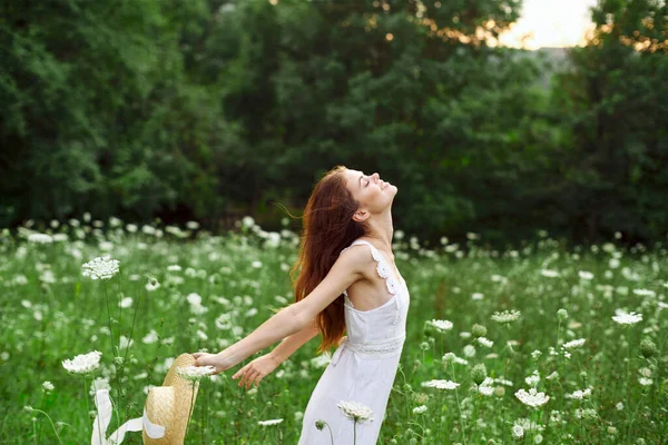 Femme en robe blanche chapeau tenant fleurs nature promenade — Photo