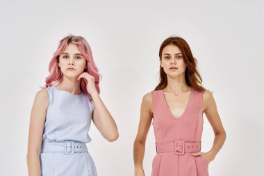 İki kız arkadaş yan yana durmuş, moda zevkini sergiliyorlar.