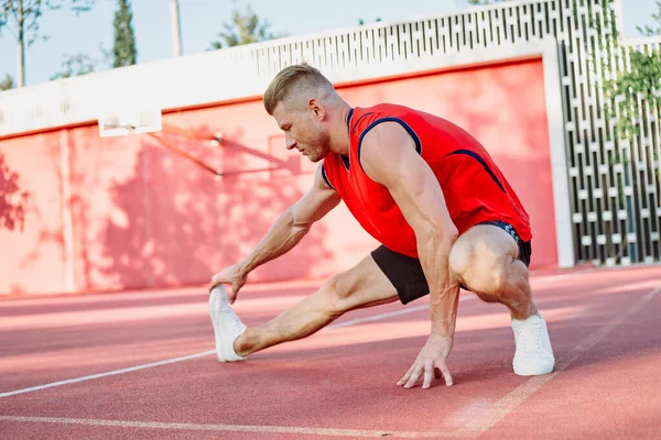 Spor salonunda spor yapan kırmızı tişörtlü bir adam egzersiz yapıyor. — Stok fotoğraf