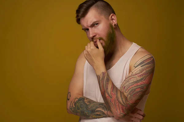 흰색 티셔츠를 입고 팔에 문신을 하고 있는 수염을 한 남자는 심각 한 표정을 짓고 있다 — 스톡 사진