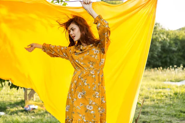Usmívající se žena ve žlutých šatech pózuje příroda žlutá látka — Stock fotografie