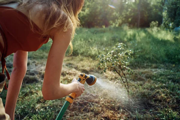 Kvinna vattning träd i trädgård landsbygd sommar jordbruk — Stockfoto