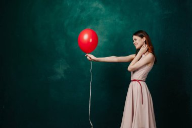 Kırmızı balonlu kadın yeşil arka planda tatil eğlencesi