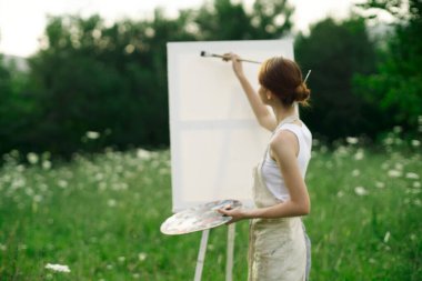 Kadın ressam açık havada yaratıcı manzara çiziyor.