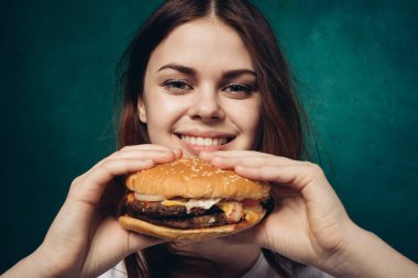 Hamburgerli neşeli kadın fast food yiyor.