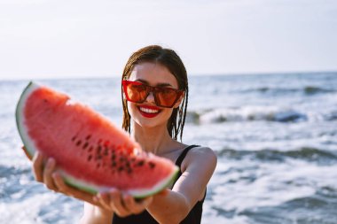 Siyah mayo giymiş neşeli güzel bir kadın karpuz moda seyahati
