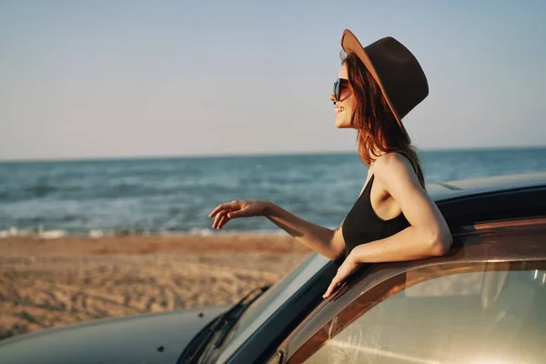 Hübsche Frau mit Sonnenbrille in der Nähe des Autos am Strand — Stockfoto