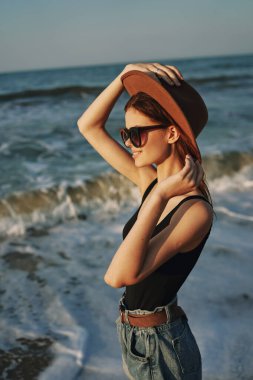 Kumsalda yürüyen bir kadın, tatil güneşinde seyahat ediyor.
