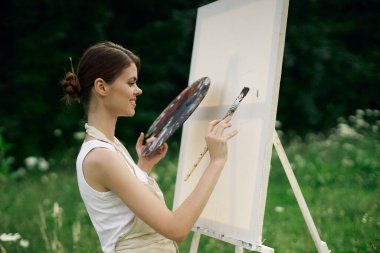 Resim paleti olan kadın ressam doğa hobisi çiziyor.