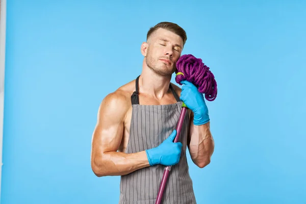 Een man in een schort met een dweil in zijn handen schoonmaakdienst — Stockfoto