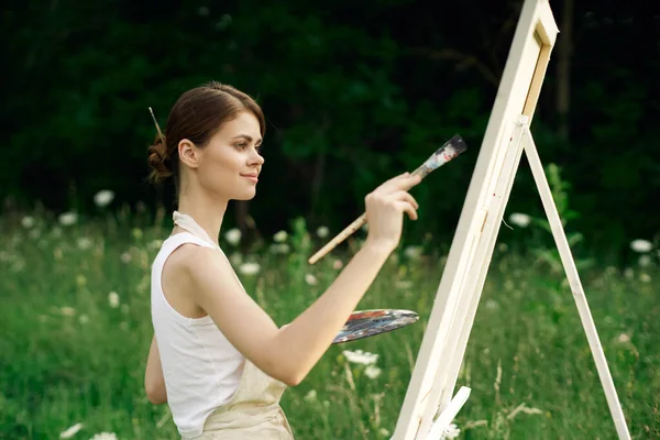 Cheerful woman artist painting a picture outdoors creative art — Stock Photo, Image