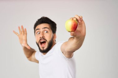 Beyaz tişörtlü sakallı adam, elma sağlığına uygun beslenme.