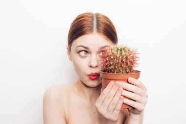 Ellerinde kaktüs olan çıplak omuzlu bir kadın.