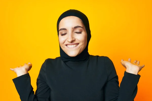 穆斯林，头戴黑色头巾，摆出时尚手势，手执黄色背景 — 图库照片