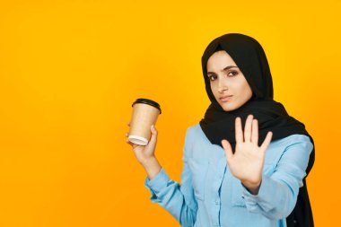 İçki içen siyah tesettürlü kadın duygusal rahatlama sarı arka plan