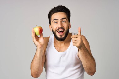 Beyaz tişörtlü bir adam. Ellerinde elma. Sağlıklı yiyecekler.