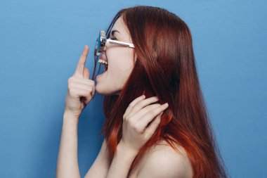 Çıplak omuzlu, gözlüklü, mavi arka planlı çekici bir kadın.