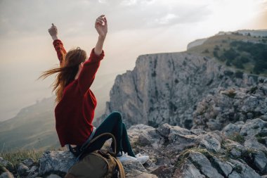 Kadın yürüyüşçü dağ manzarasında oturuyor. Temiz hava.