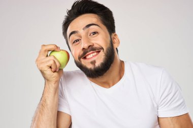 Elması beyaz tişörtlü, meyveli neşeli bir adam.
