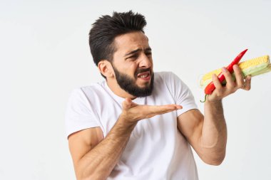 Elinde sebzelerle sakallı bir adam. Sıcak biberli mısır.