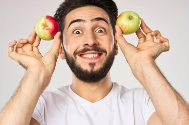 Elması beyaz tişörtlü, meyveli neşeli bir adam.