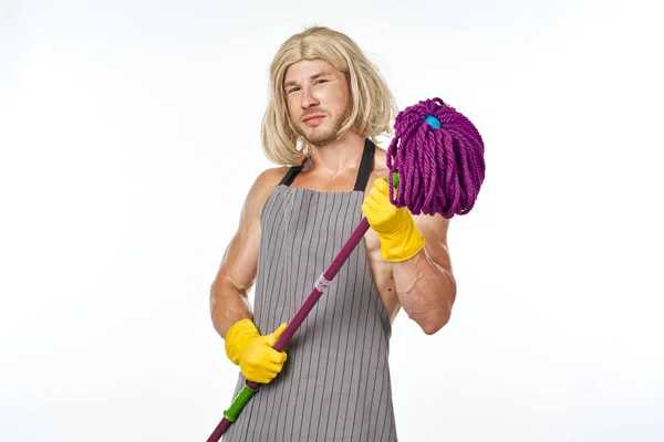 Muscular man in apron with a mop in a womans wig — Stock Photo, Image