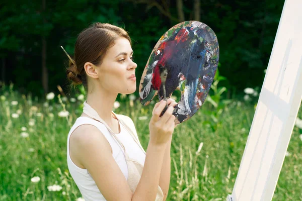 Veselá žena maluje obraz paleta příroda krajina — Stock fotografie