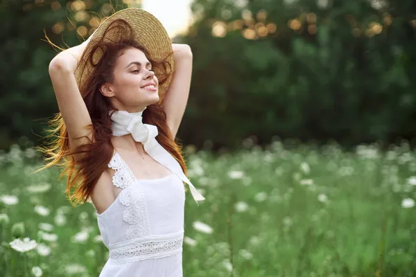 Belle femme dans un chapeau dans un champ avec des fleurs marche — Photo